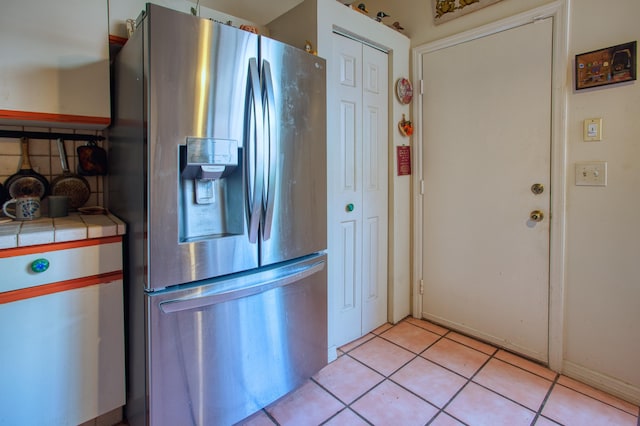 kitchen with light tile patterned floors, stainless steel fridge, and tile countertops
