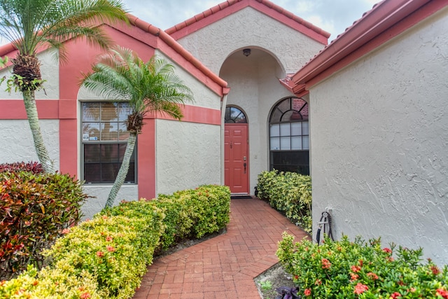 doorway to property featuring stucco siding and a tile roof