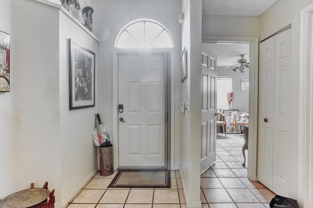 entryway featuring light tile patterned floors, a textured ceiling, and ceiling fan