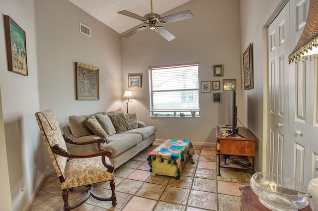 living room featuring baseboards, visible vents, lofted ceiling, ceiling fan, and a textured ceiling