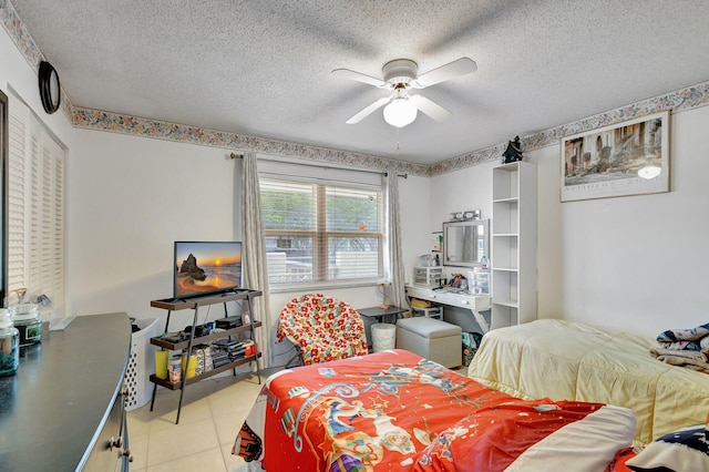 bedroom featuring ceiling fan, light tile patterned floors, and a textured ceiling