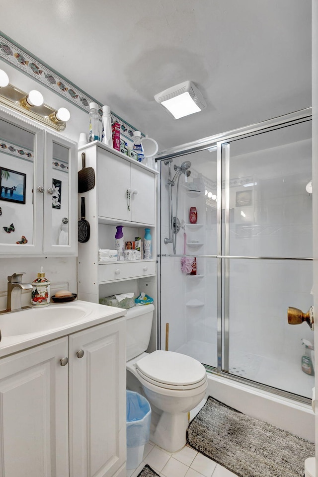 bathroom featuring tile patterned flooring, walk in shower, vanity, and toilet