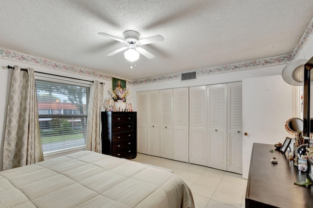 tiled bedroom featuring ceiling fan, a closet, and a textured ceiling