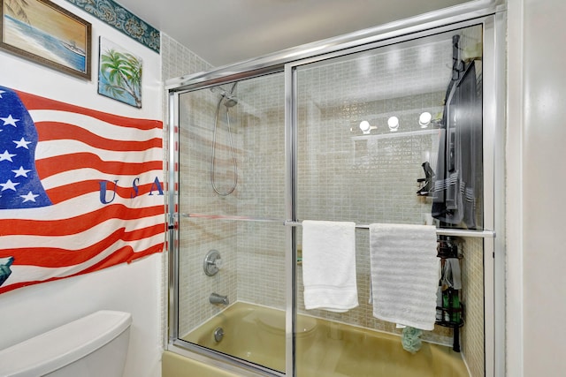 bathroom with bath / shower combo with glass door and toilet