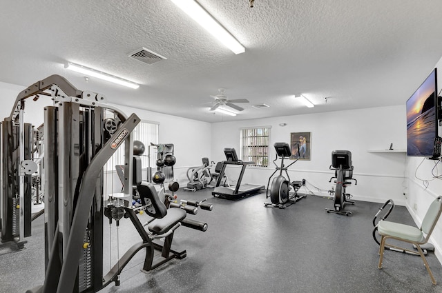 gym with ceiling fan and a textured ceiling