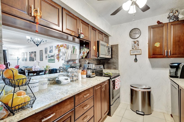 kitchen with stainless steel appliances, light stone countertops, light tile patterned floors, and ceiling fan