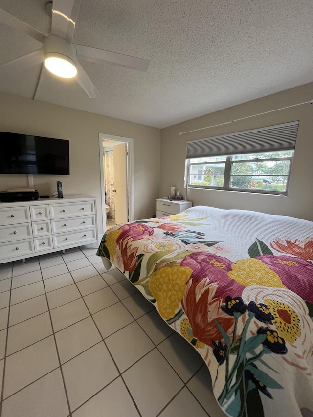 bedroom with ceiling fan, connected bathroom, a textured ceiling, and light tile patterned floors