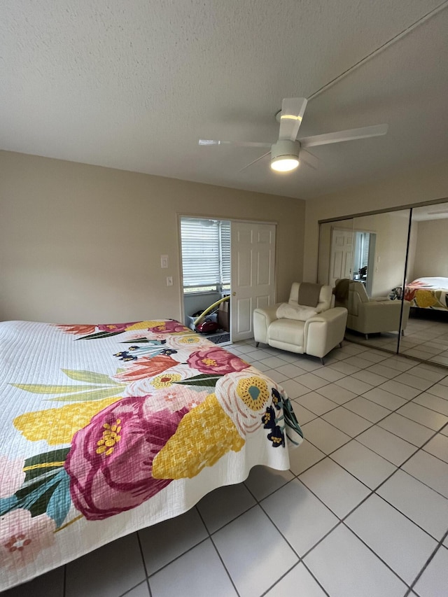 bedroom featuring tile patterned floors, a closet, ceiling fan, and a textured ceiling