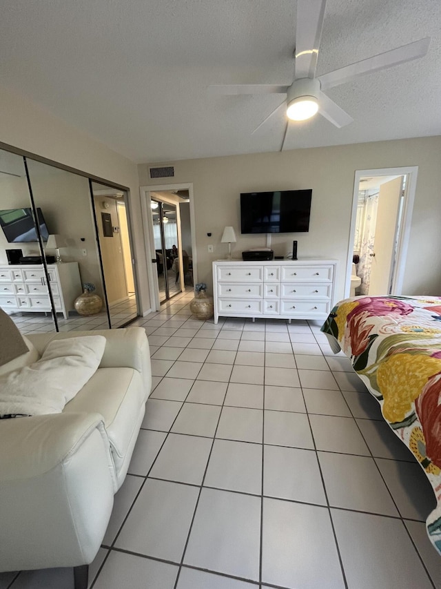 tiled bedroom featuring ensuite bathroom, a closet, ceiling fan, and a textured ceiling