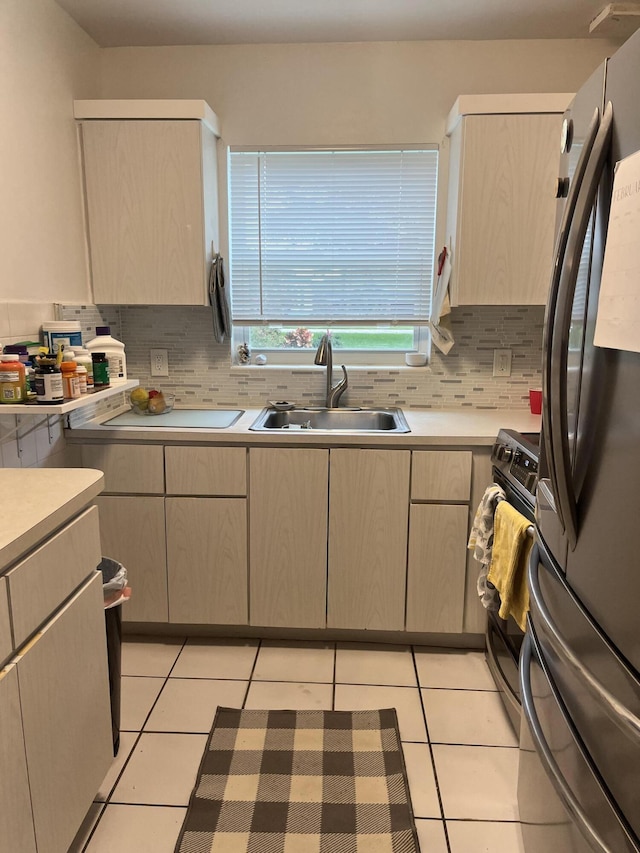 kitchen featuring stainless steel refrigerator, black electric range oven, light tile patterned floors, and sink