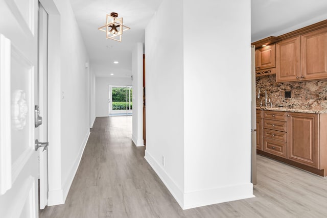 hallway featuring an inviting chandelier and light hardwood / wood-style flooring