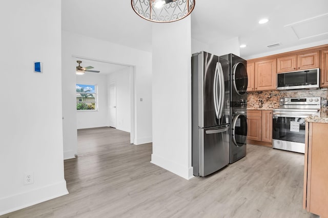 kitchen with stainless steel appliances, stacked washing maching and dryer, ceiling fan, and light hardwood / wood-style floors