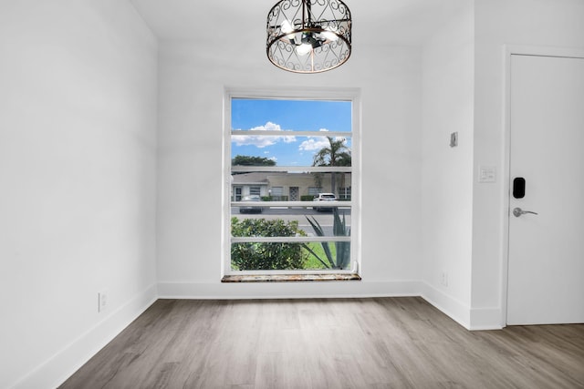 unfurnished dining area with wood-type flooring, a chandelier, and plenty of natural light