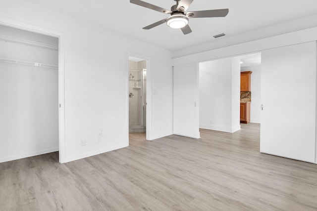 unfurnished bedroom featuring a closet, connected bathroom, ceiling fan, and light wood-type flooring