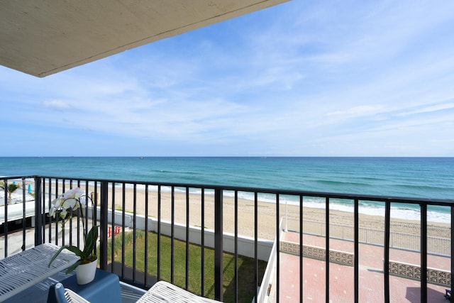 balcony with a water view and a view of the beach