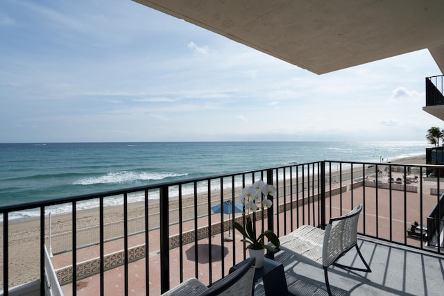 balcony with a water view and a view of the beach