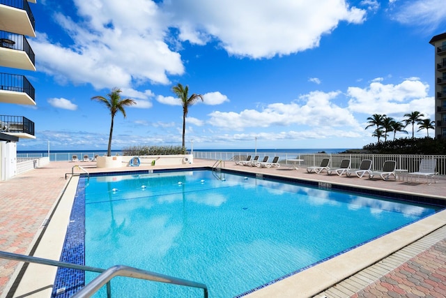 view of pool featuring a water view and a patio