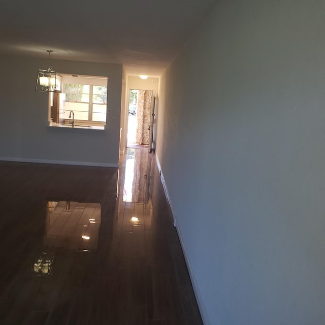 corridor with sink, an inviting chandelier, and dark hardwood / wood-style floors