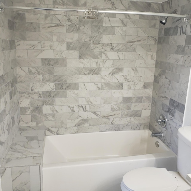 bathroom with tiled shower / bath combo and toilet