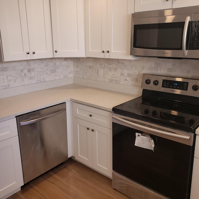 kitchen featuring appliances with stainless steel finishes, white cabinetry, and light hardwood / wood-style floors