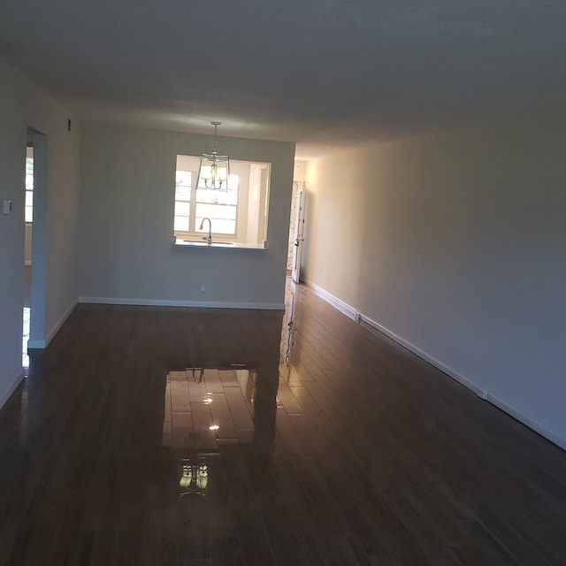 empty room featuring sink, a notable chandelier, and dark hardwood / wood-style floors