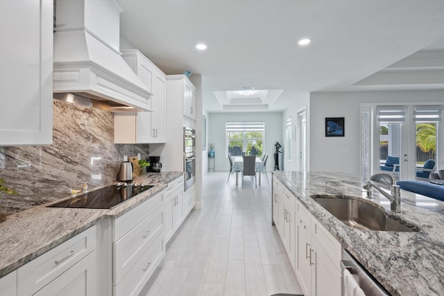 kitchen featuring sink, white cabinetry, custom range hood, decorative backsplash, and black electric cooktop