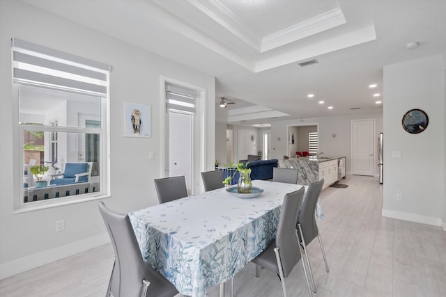 dining area with sink, a raised ceiling, ceiling fan, and crown molding