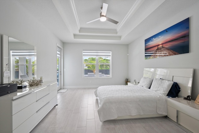 bedroom featuring light wood-type flooring, a raised ceiling, ceiling fan, and crown molding