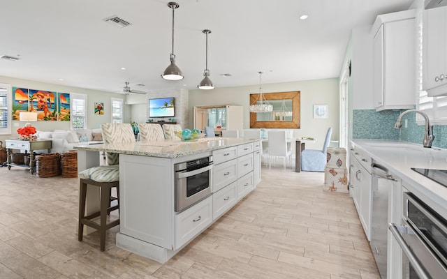 kitchen featuring stainless steel oven, a center island, white cabinetry, and a kitchen breakfast bar