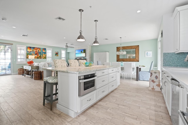 kitchen featuring white cabinetry, a breakfast bar, a kitchen island, oven, and pendant lighting