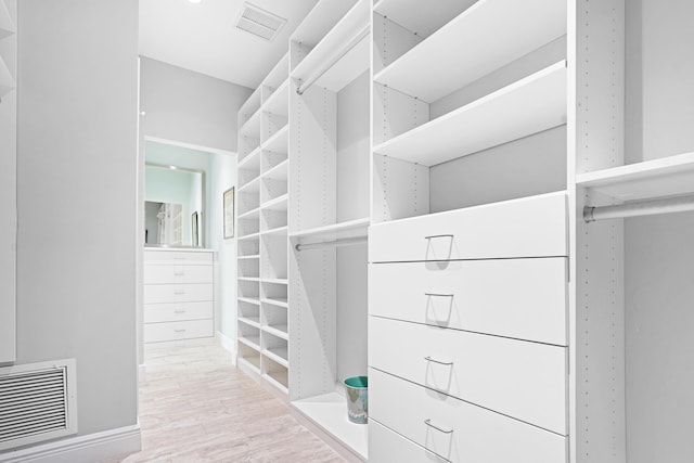 walk in closet with light hardwood / wood-style floors