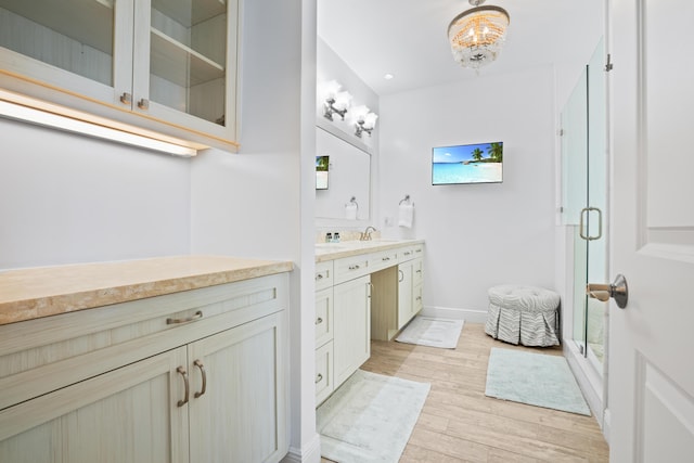 bathroom featuring a shower with door, vanity, a notable chandelier, and wood-type flooring