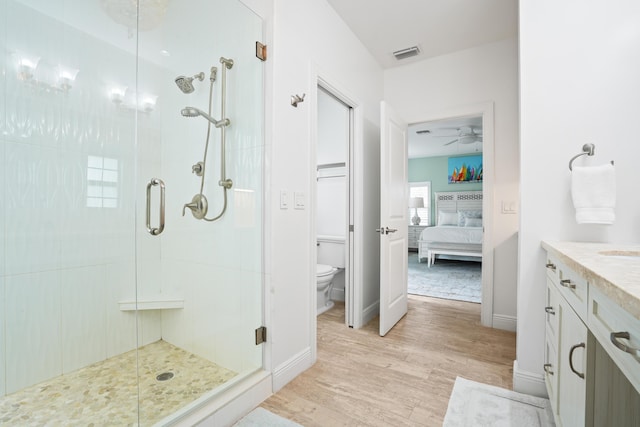 bathroom featuring hardwood / wood-style flooring, toilet, ceiling fan, vanity, and walk in shower