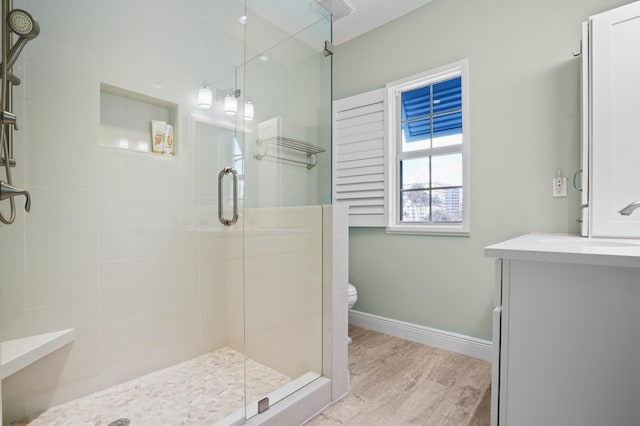 bathroom featuring hardwood / wood-style flooring, vanity, an enclosed shower, and toilet