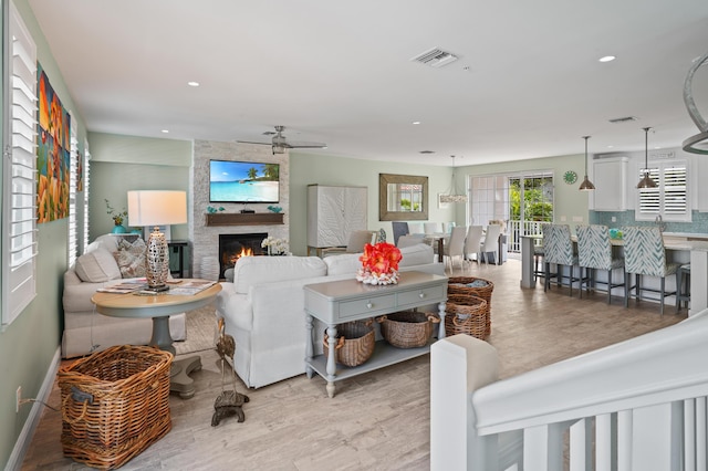 living room with a large fireplace, ceiling fan, and light hardwood / wood-style floors