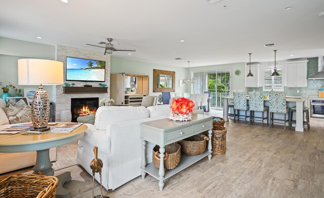 living room with a fireplace, light hardwood / wood-style flooring, and ceiling fan