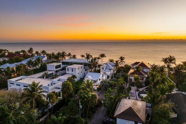 aerial view at dusk with a water view and a residential view