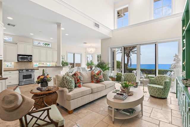 living room with recessed lighting, visible vents, a towering ceiling, and stone tile floors