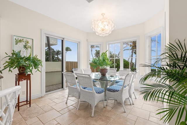 dining space with stone tile flooring, baseboards, and an inviting chandelier