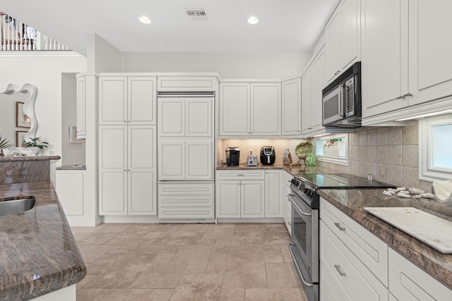 kitchen featuring dark stone counters, tasteful backsplash, visible vents, and stainless steel electric stove