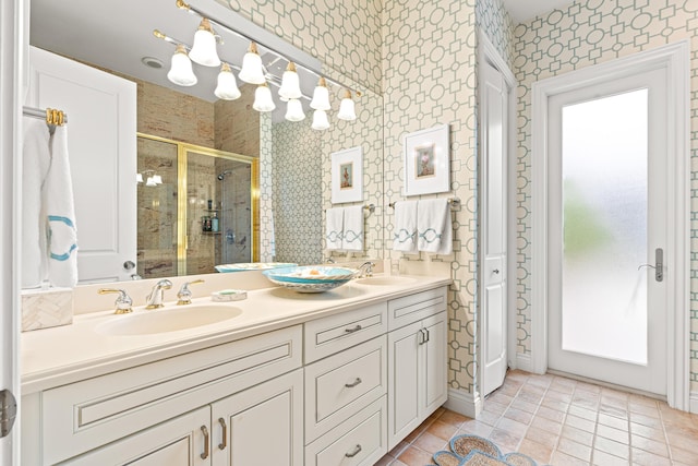 full bathroom with a stall shower, double vanity, a sink, and wallpapered walls