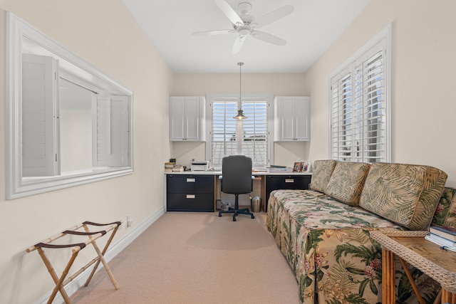 office space with light carpet, baseboards, built in desk, and a ceiling fan