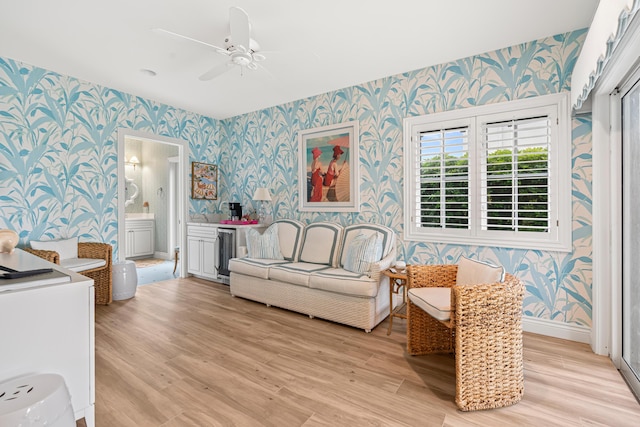 interior space featuring wine cooler, light wood-style flooring, baseboards, ensuite bath, and wallpapered walls