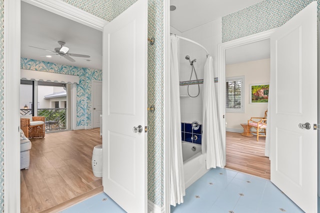 bathroom with a ceiling fan, shower / tub combo with curtain, baseboards, and wallpapered walls