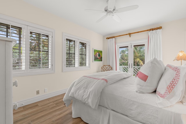 bedroom featuring baseboards, multiple windows, wood finished floors, and access to exterior