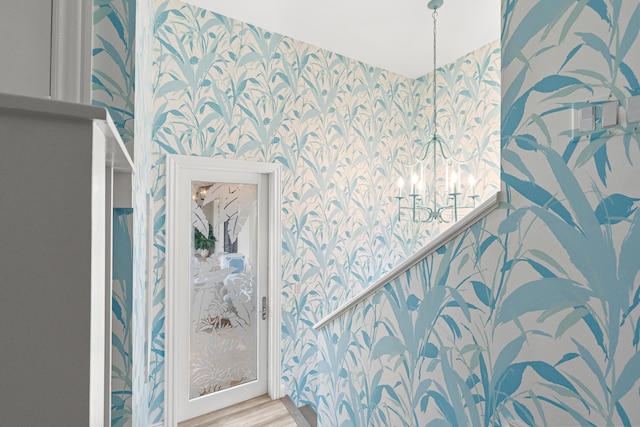 bathroom with wallpapered walls, wood finished floors, and an inviting chandelier