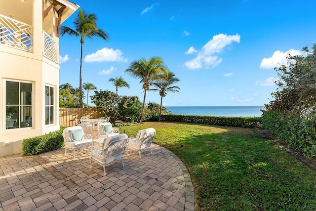 view of patio with a water view and fence