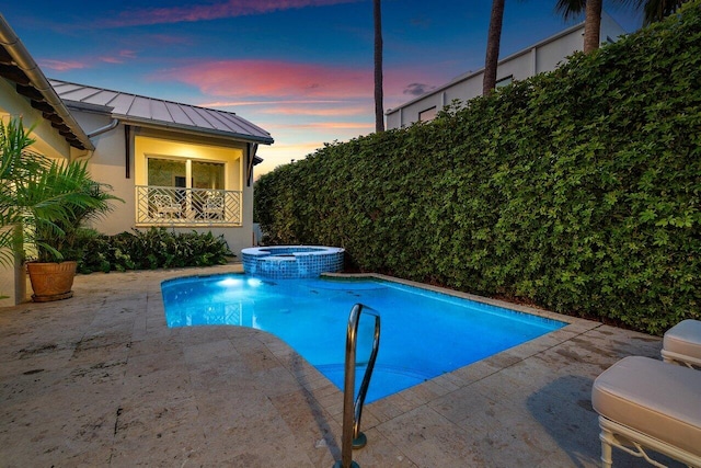 pool at dusk featuring a patio area and a pool with connected hot tub