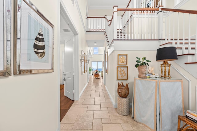 foyer entrance with stone tile floors, visible vents, baseboards, stairs, and ornamental molding