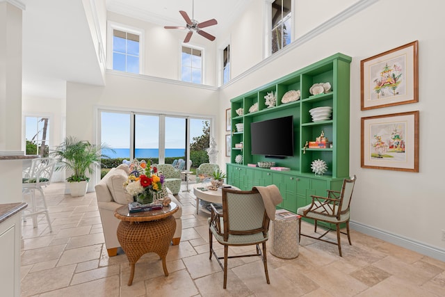 interior space featuring baseboards, a healthy amount of sunlight, a ceiling fan, and stone tile floors